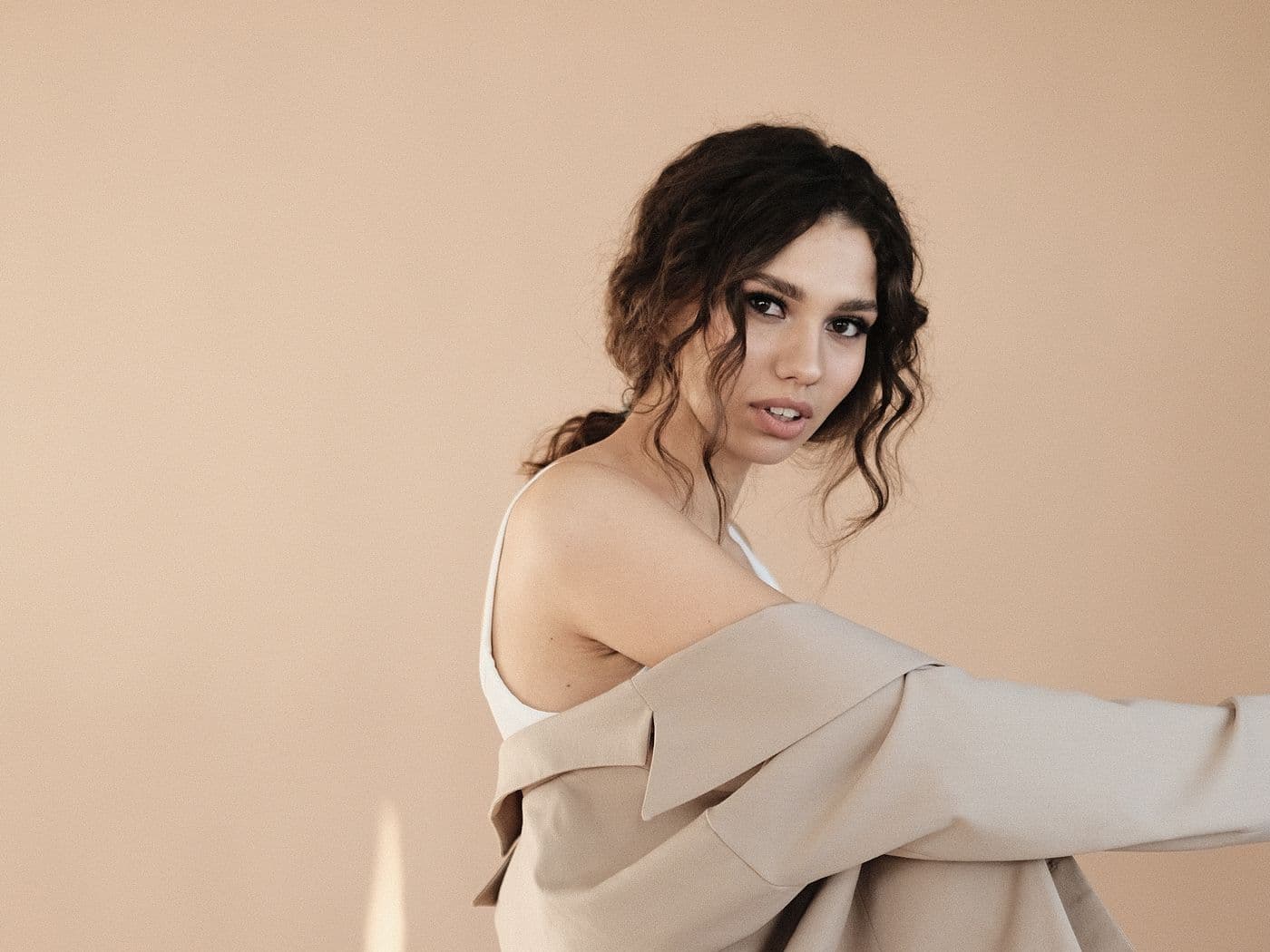 Model in a beige blazer against a warm backdrop